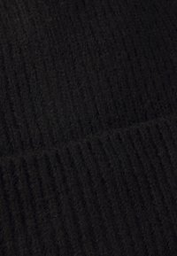 Tessuto a maglia nero a coste, che mostra una consistenza morbida e una profondità, con fibre visibili che creano un aspetto caldo e uniforme.
