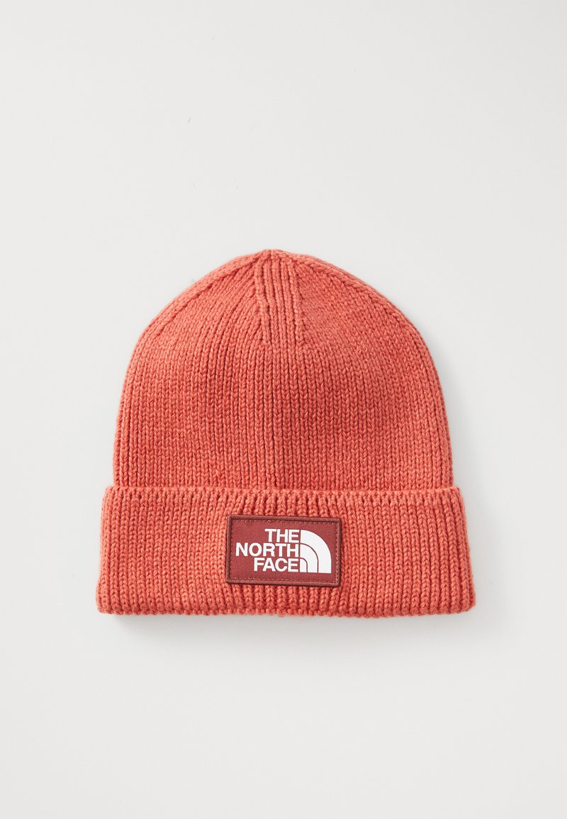 Coral orange knit beanie with folded cuff and rectangular patch logo of The North Face in white and red on front center.
