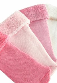 Tre par rosa strumpor med varierande texturer: ett par med fluffiga frottékanter, ett med slät stickning och ett i helt ljusrosa.