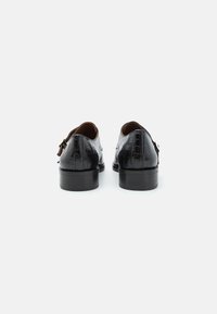 Schwarze Lederschuhe mit einem kroko-prägierten Muster, ausgestattet mit einem niedrigen Absatz und einer Schnallendetail. Glatte Textur in einem klassischen Design.