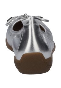 Metaliczne srebrne baletki o gładkim wykończeniu, zaokrąglonym czubku, wyciętych bokach i plecionym woalem z przodu. Brązowa gumowa podeszwa.