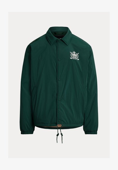 Tume roheline nööpidega jakk kraega, elastsete varrukaotsadega, esimestes taskutes, nööriga äärega ja valge tikandiga vapiga rinnal.