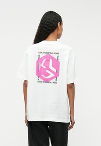 Λευκό βαμβακερό t-shirt με ροζ εξάγωνο γραφικό που διαθέτει λογότυπο και κείμενο "KARL LAGERFELD JEANS" εκτυπωμένο στην πλάτη. Κοντά μανίκια.