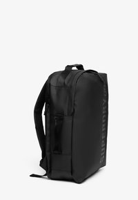 Zwarte rugzak met een gladde, matte afwerking. Beschikt over verstelbare schouderbanden, een zijvak en bedrukte branding aan de voorkant. Lichtgewicht design.