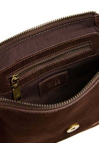 Unutrašnjost smeđe zamenske torbe s patentnim zatvaračem i tkaninskom oblogom, s zlatnim patentnim zatvaračem i kružnim zlatnim dugmetom.