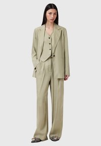 Ljus olivgrön tre-delad kostym bestående av en blazer, väst och vida byxor, tillverkad av ett glatt tyg med en elegant finish.