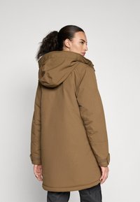 Hnedá parka s kapucňou, ktorá má rovný strih, textúrovanú tkaninu a akcenty na manžetách s suchým zipsom. Pohľad zobrazuje bundu zozadu.