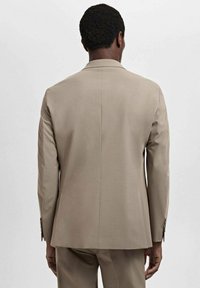 Beige suit jacket with a tailored fit, smooth texture, and single vent at the back. Features buttoned cuffs and a clean, minimalist design.