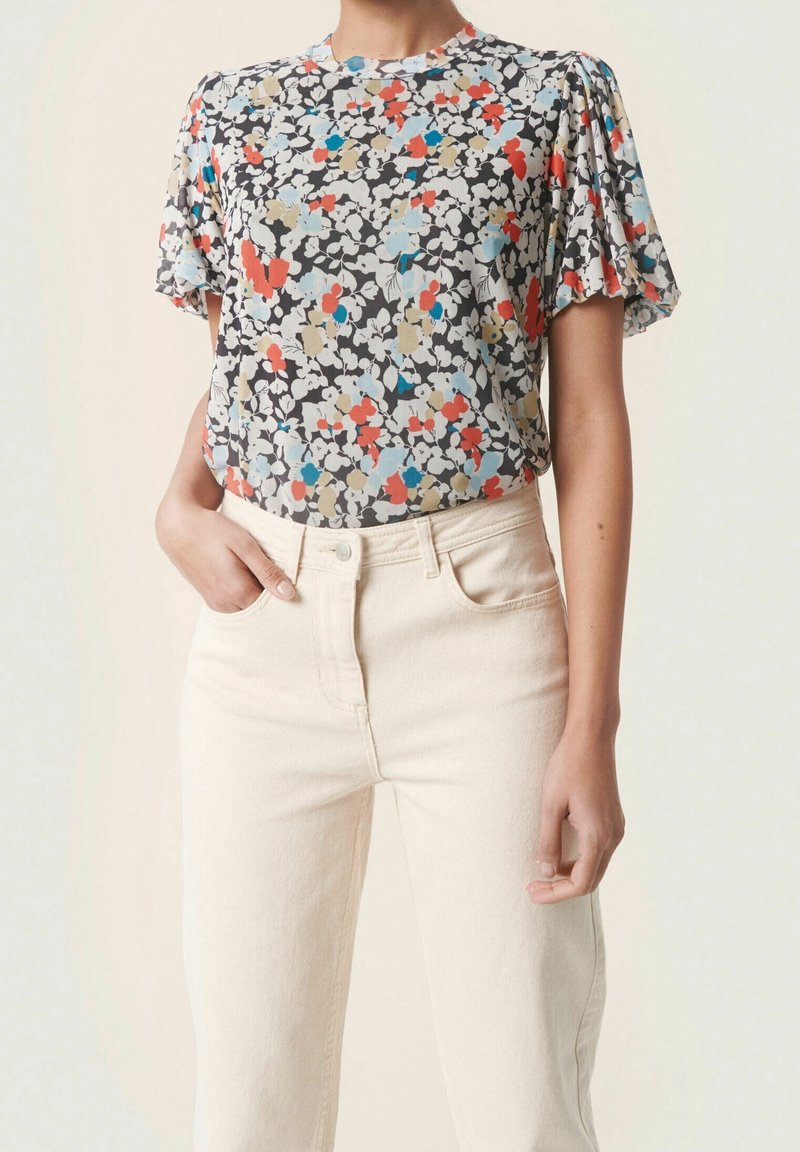 Kortärmad blommig topp i grått, med ett flerfärgat blommönster med röda, blå och beige accenter. Mjuk tyg med en avslappnad passform.