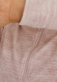 Lichtroze zip-up jack van zachte, textuurstof met een opvallende rits en een discrete stiknaad, en een iets bredere manchetdetail.