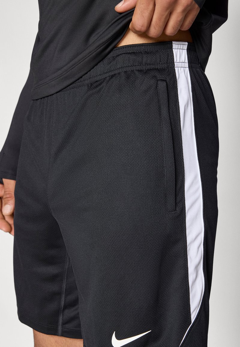 Schwarze Sportshorts mit strukturiertem Stoff, elastischem Bund, Seitentaschen und weißen Akzentstreifen. Verfügen über ein kleines weißes Logo nahe dem Saum.