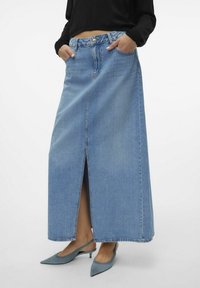 Denim maksi sijonas su priekiu išpjovimu, šviesiai mėlynos spalvos, dviem kišenėmis ir sagų juosmeniu. Dėvimas su smailiais mėlynais batais.