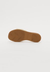 Sandal såle med en teksturert brunt gummi overflate. Har bølgete mønster for grep, og preget merkevare navn "REEF" nær hælen.