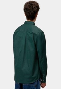Camicia button-down verde scuro con maniche lunghe, dettaglio sulla parte posteriore e polsini regolabili, realizzata in un cotone leggero e morbido.