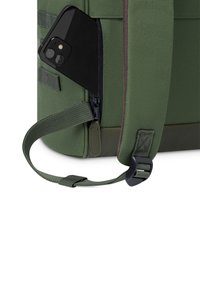 Groene stoffen tas met een zijrits, met een zwarte smartphone die gedeeltelijk is ingestoken. Bevat webbing en een plastic gesp. Textuur onderkant.