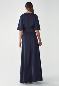 Navy blue, floor-length dress with short bell sleeves and a concealed zipper closure at the back. Smooth, satin-like texture.