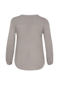 Blouse à manches longues, de couleur gris clair, avec un col arrondi, une texture douce, un détail de pli au dos et des poignets avec boutons. Aucun motif ni élément métallique visible.