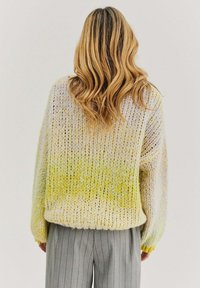 Pletací svetr s oversized strihom, s žltým a levanduľovým gradientom. Hrubá priadza vytvára textúrovaný a príjemný vzhľad.