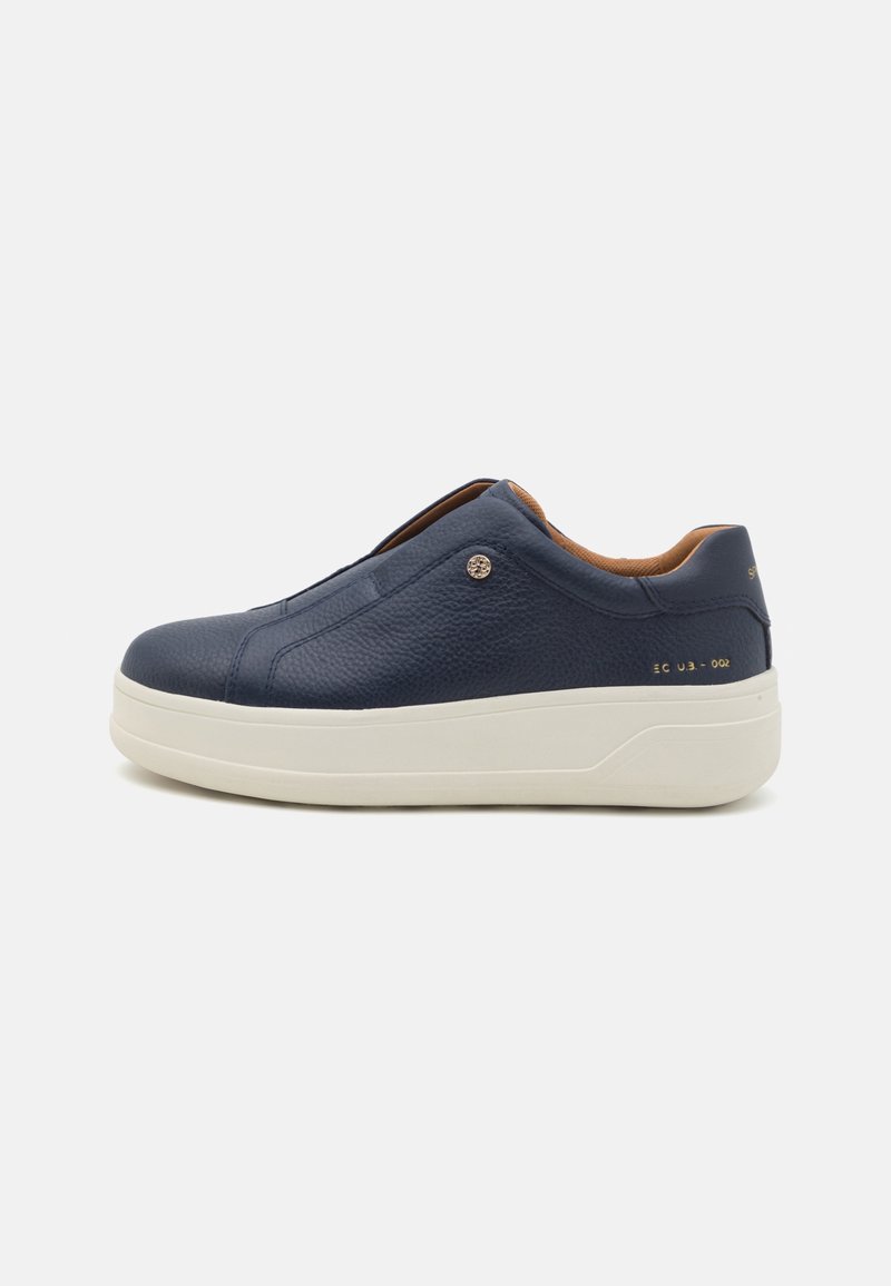 Baskets à enfiler en cuir bleu marine avec semelle blanche épaisse et coutures discrètes, présentées de profil sur un fond uni.