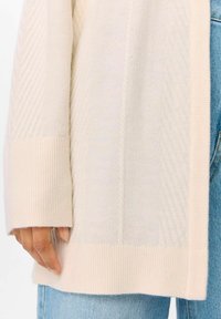 Il cardigan lavorato a maglia di un leggero color beige chiaro presenta polsini e orlo a costine, con un motivo testurizzato e pannelli lisci. Tessuto morbido e leggero.