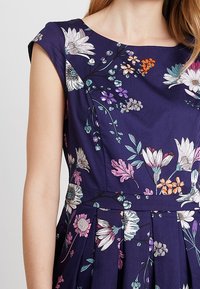Blumendruckkleid mit kurzen Ärmeln, mit navyfarbenem Hintergrund, lebhaften mehrfarbigen Blumen und einem plissierten Rockdesign.