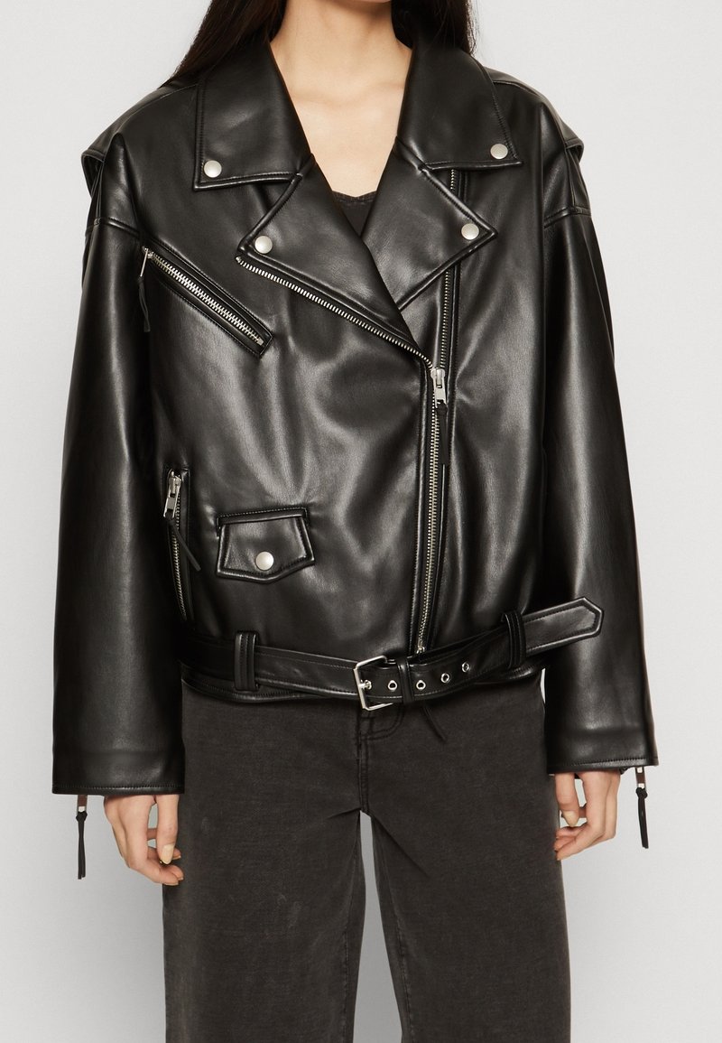 Black leather biker jacket with a cropped design, asymmetrical zippers, snap buttons, and a belted waist. Features textured finish and wide lapels.