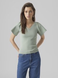 Lys grøn ribbet V-hals topp med korte pufferm, kombinert med høytlivs blå jeans. Enkel, tettsittende design.