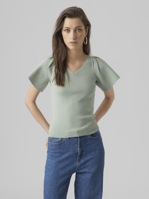 Lys grøn ribbet V-hals topp med korte pufferm, kombinert med høytlivs blå jeans. Enkel, tettsittende design.