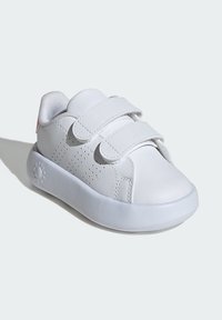 White sneaker with two Velcro straps, smooth leather upper, perforated sides, cushioned tongue, and a rounded rubber sole.