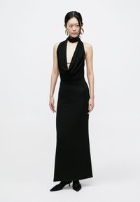 Black maxi dress with a draped neckline, form-fitting design, and smooth texture. Features halter style and a deep V-back.