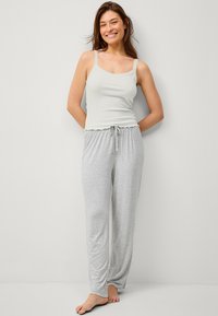 Lichtgrijze pyjama set met een aansluitend hemd met kant en een broek met trekkoord. Zachte stof, comfortabele pasvorm en eenvoudig ontwerp.