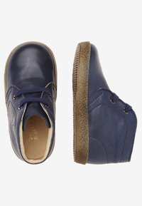Botines de cuero azul marino con puntera redonda, suelas de goma texturizadas y diseño con cordones. Acabado suave y sutilezas en las costuras.