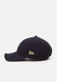 Gorra de béisbol azul marino con visera curvada, que presenta un logo en neón verde en la parte frontal y un logo más pequeño en el lateral. Tela de algodón con detalles de costura.