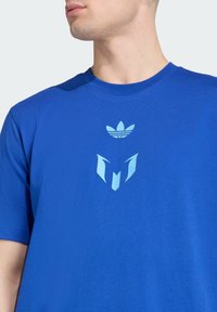 Short-sleeve blue t-shirt made of cotton. Features a centered light blue logo design on the chest with geometric shapes and stripes.