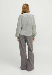 Light gray knitted sweater with a textured pattern and balloon sleeves, paired with loose-fitting gray denim pants.