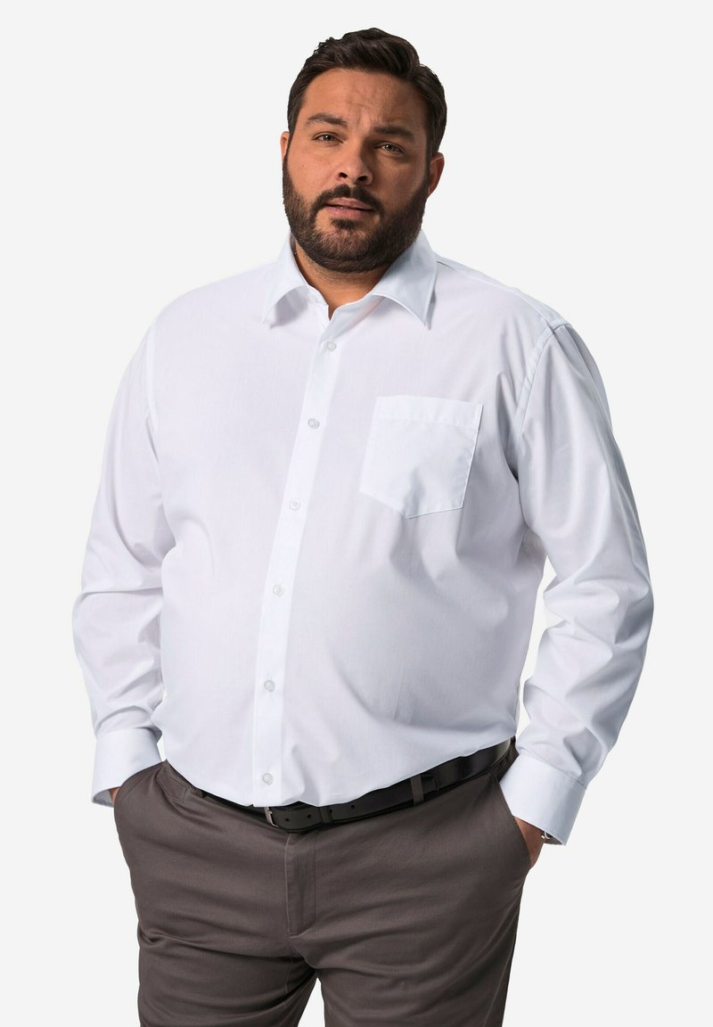 Camisa blanca de manga larga con cuello, cierre de botones en la parte delantera y un bolsillo en el pecho, combinada con pantalones oscuros de color marrón. Textura de tela suave.