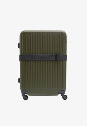 Oliwkowa, twarda walizka z pionowymi rowkami, czarny pasek do bezpiecznego zamknięcia oraz cztery kółka ułatwiające mobilność.