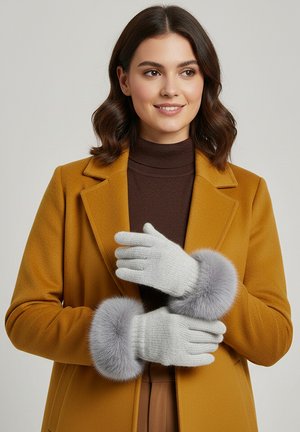 Graue Strickhandschuhe mit einem weichen grauen Pelzbund. Das Modell trägt einen braunen Rollkragenpullover unter einem senffarbenen Mantel, die Hände sind vorn positioniert.