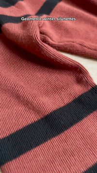 Gros plan sur un tissu rouge côtelé avec de larges rayures noires horizontales, plié avec le texte « Silhouettes hivernales géométriques » visible.