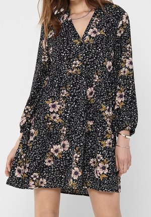 Schwarzes Blumen-Kleid mit langen Puffärmeln, V-Ausschnitt und einem ausgestellten Saum. Mit weißen, rosa und goldenen Blumenmustern durchzogen. Leichter Stoff.