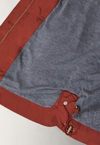 Inredning av röd och blå jacka, med en slät textur, en dragkedja och en snörning med en metalljustering för anpassning.