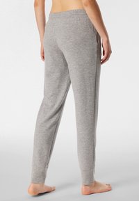Gray cotton sweatpants with a relaxed fit, elastic waistband, side pockets, and fitted cuffs at the ankles. Soft texture.