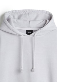 Haut à capuche blanc avec un cordon de serrage, texture douce, et étiquette Vans au niveau du cou. Présente des détails de poignet côtelés et une coupe décontractée.