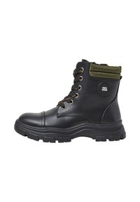 Botines negros con acabado de piel lisa, cuello de textil verde, lengüeta acolchada, cordones naranjas y suela de goma resistente con patrón de tracción.
