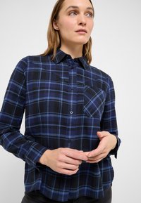 Tumši zils un zils rūtainas flaneļa krekls ar pogājamām apkaklītēm, priekšējo kabatu un garām piedurknēm. Mīksta faktūra, ērta piegrieztne.