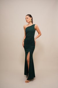 Ein schulterfreies, dunkelgrünes Abendkleid mit seitlichen Rüschen und einem hohen Schlitz. Gefertigt aus glattem Stoff, akzentuiert mit minimalen Verzierungen.