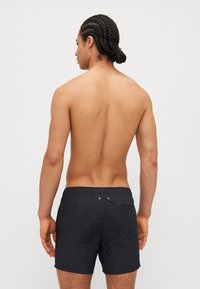 Sorte svømmedrakter laget av lett materiale, med elastisk midjebånd, sidelommer og en baklomme med klaff.