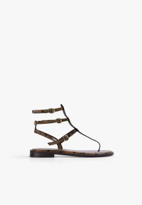 Sandalias planas con tiras, con un diseño de patrón de reptil en negro y marrón. Cuenta con tres correas ajustables con hebillas en tono dorado y una suela plana.
