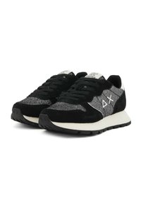 Un paio di sneakers nere e grigie con suole bianche, lacci e logo laterale, posizionate in un angolo per mostrare la parte anteriore e il lato esterno.