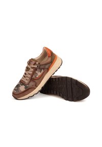 Zapatillas marrones y beige con patrón de camuflaje, detalles en naranja y suela de goma con textura antideslizante. Incluyen cierre con cordones y parte superior de tela.